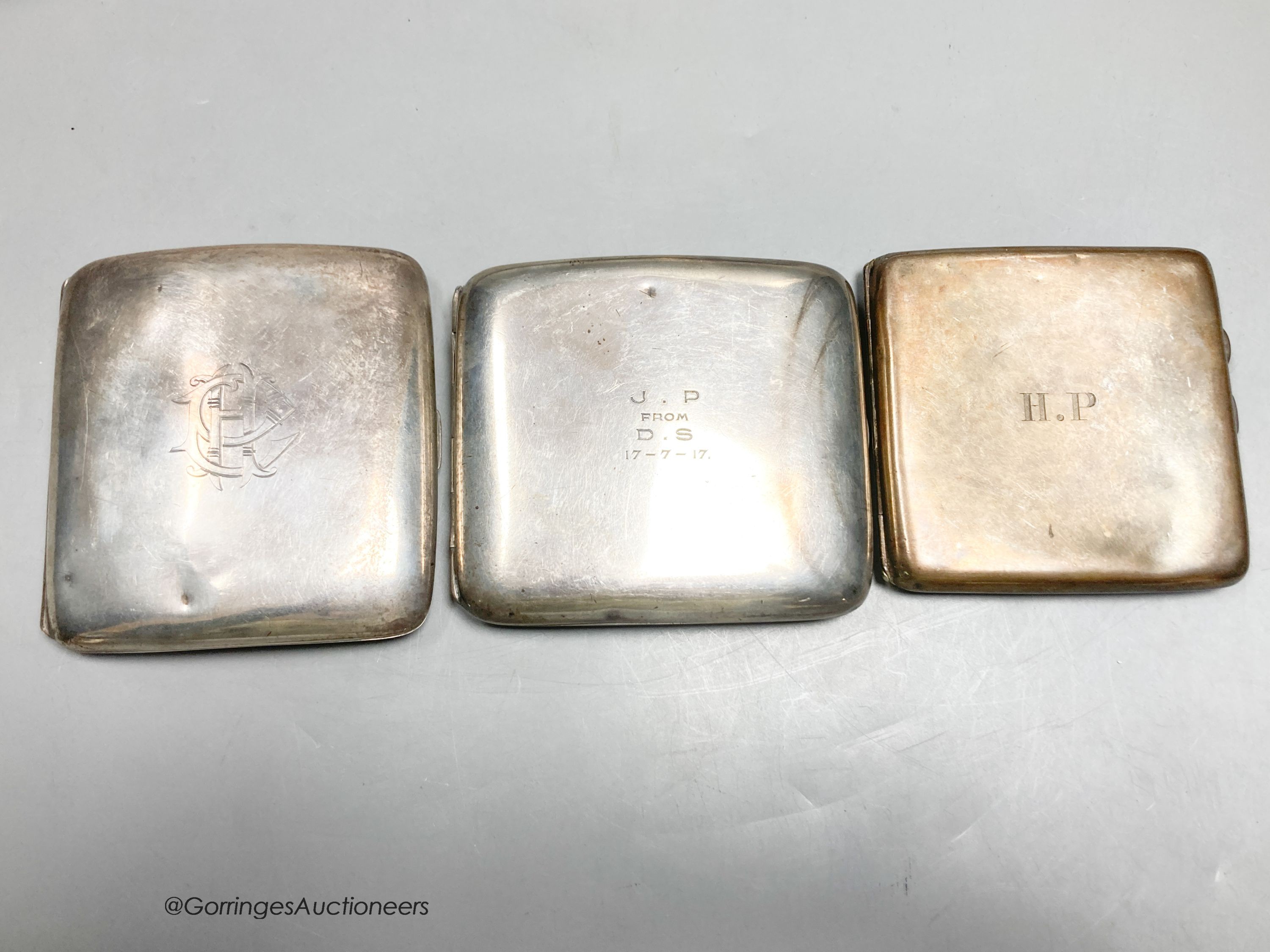 A George V silver mounted hand mirror and three silver cigarette cases.
